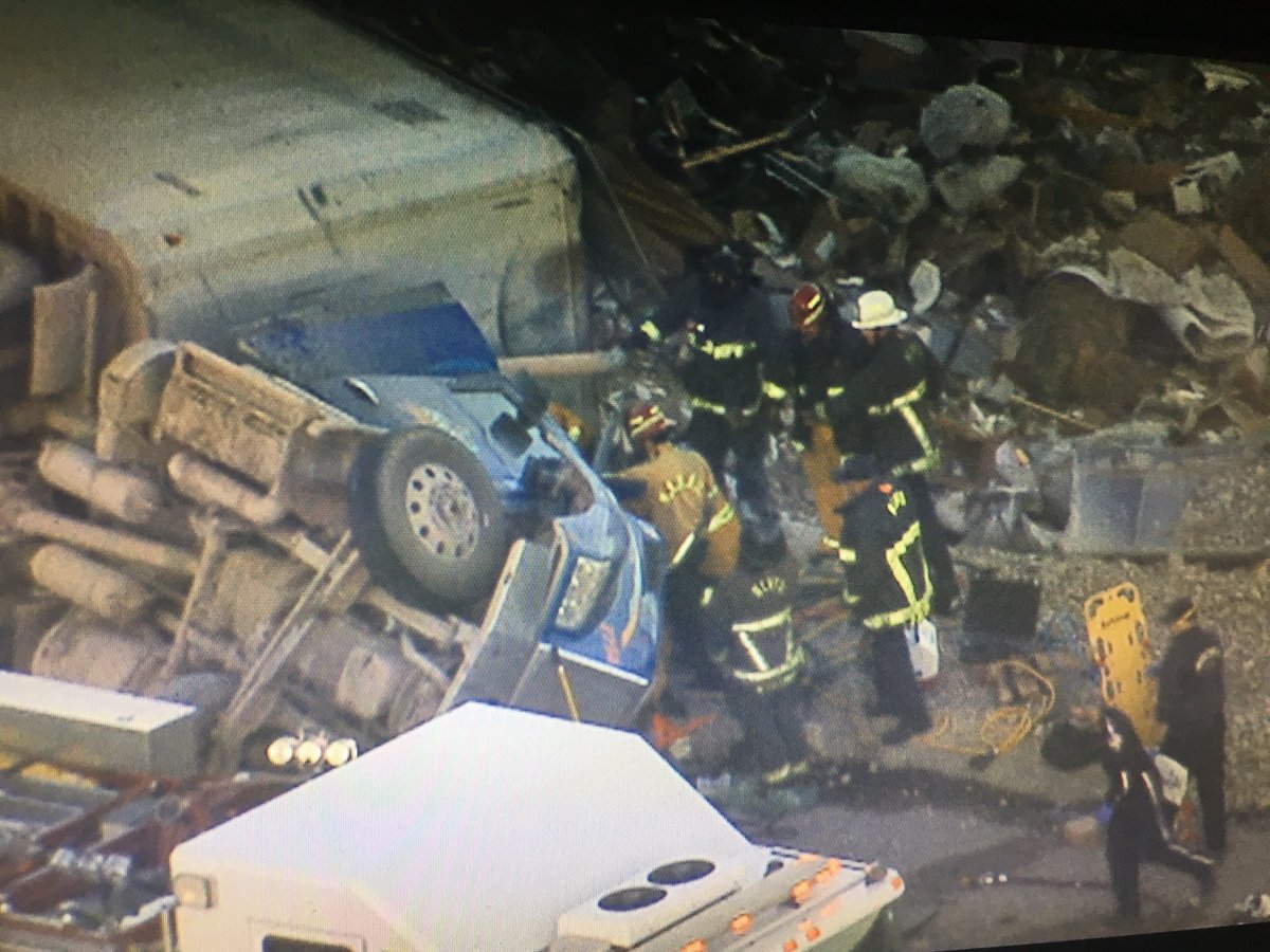 Looks like trash hauler flipped on way to landfill.  Rolled over on exit from I-15 NB to US93 (just outside Valley to the NE). Mercy Air helicopter on ground, and team of firefighters working to extract trapped driver